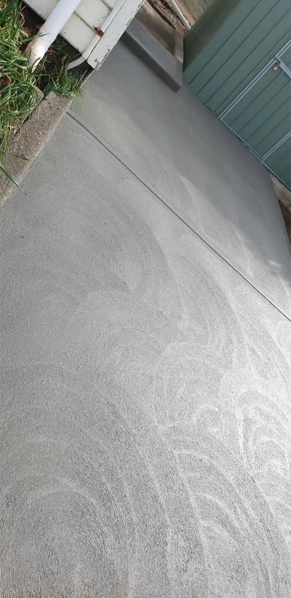 A washed aggregate driveway apron finished beside a garden bed