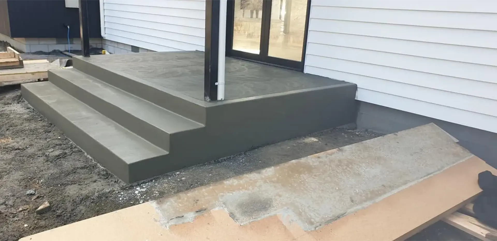 A completed concrete pathway running past a home towards the street