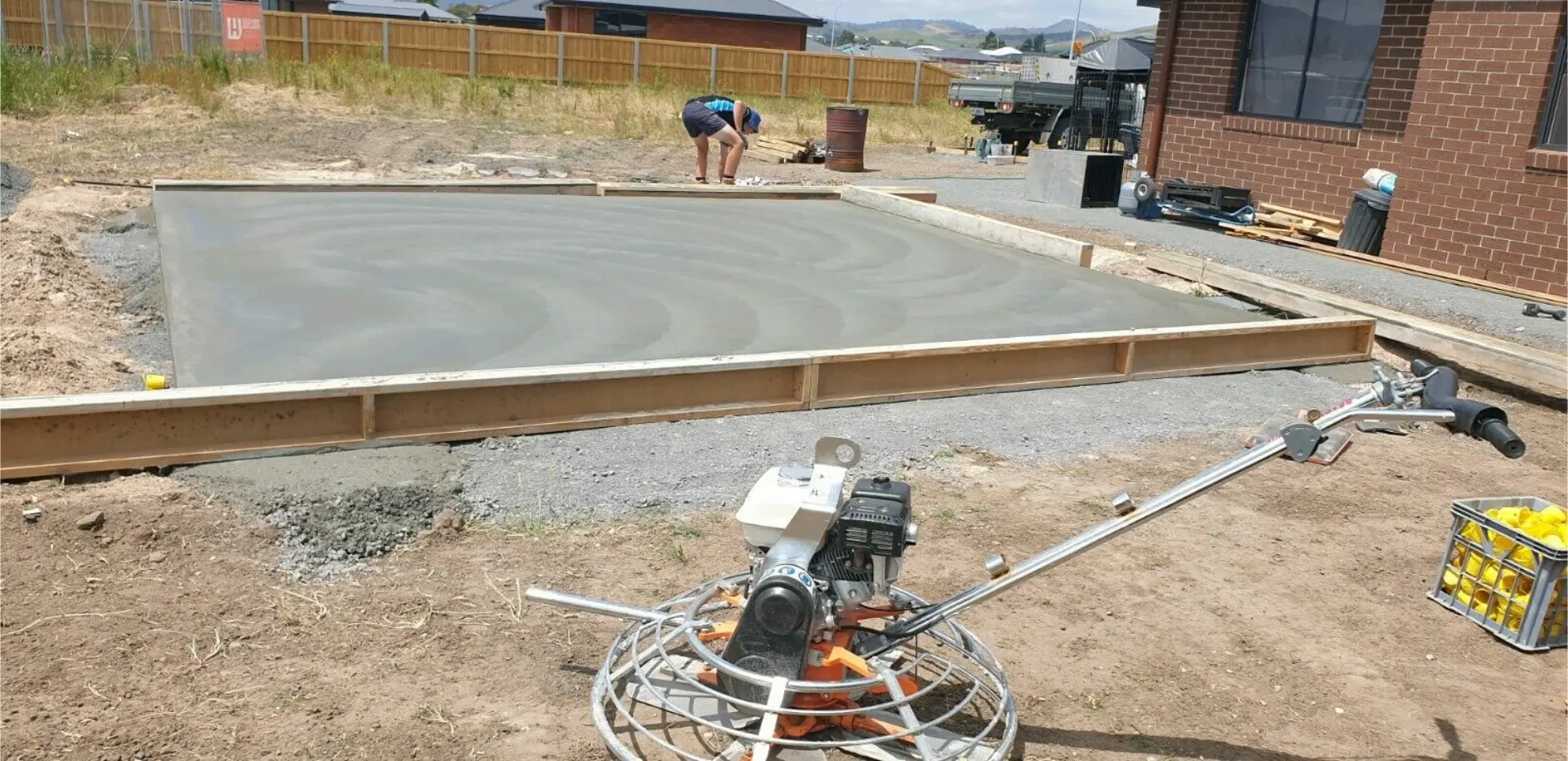 A concreter power-trowelling a large formed-up slab on a residential site