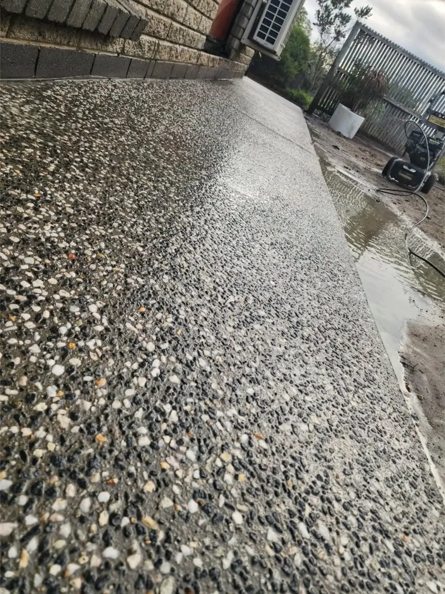 A pale exposed aggregate surface finished beside a paved courtyard
