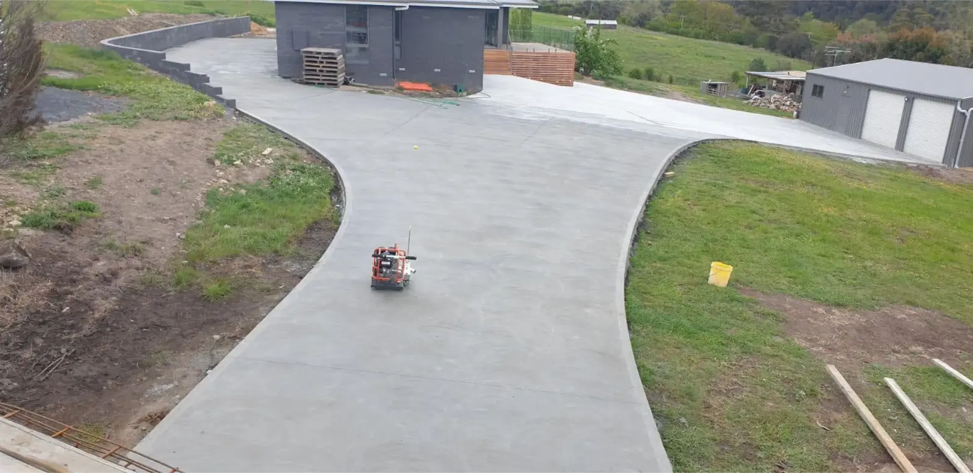 A sweeping concrete driveway laid across a grassed rural property