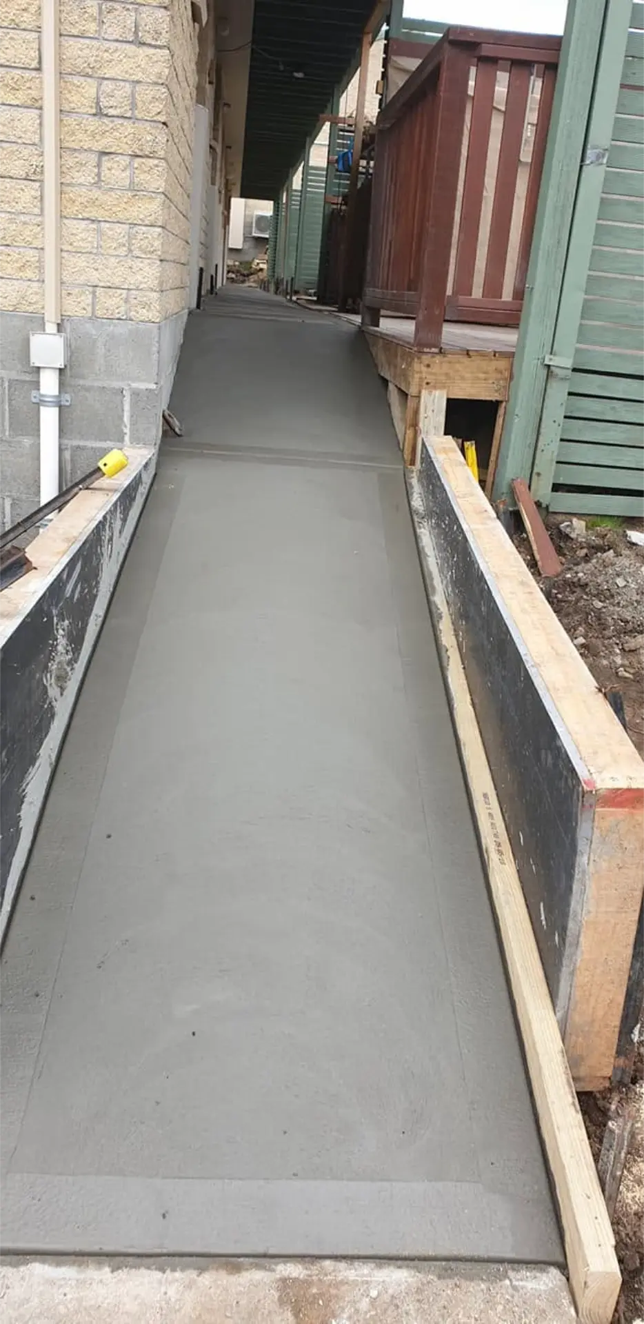 A freshly finished walkway curving along the wall of a suburban home
