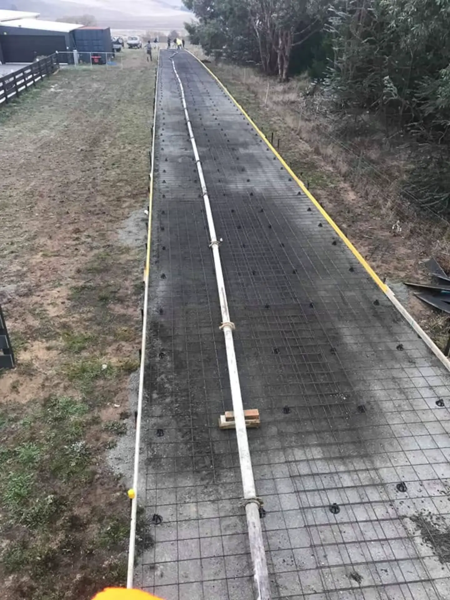 A finished concrete driveway running along a brick house to the garage