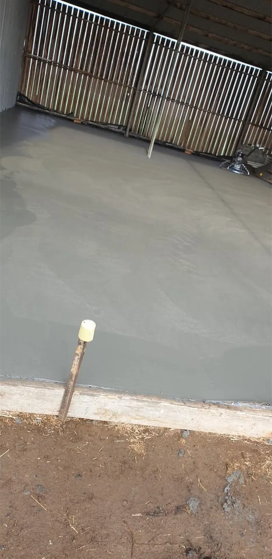 A crisp new slab edge poured against a metal fence line