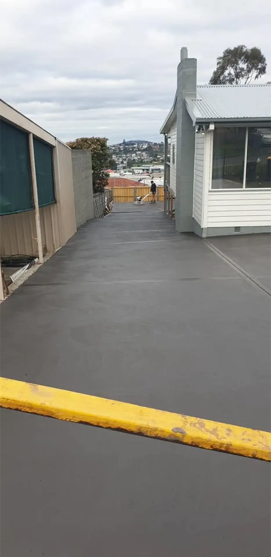A finished concrete path and patio edge beside a weatherboard house