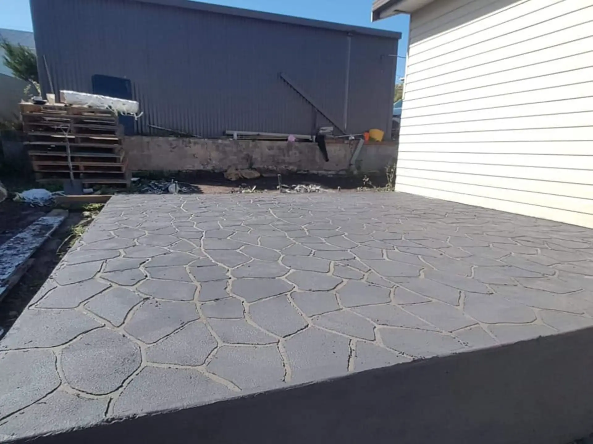 A stamped crazy-paving pattern concrete area laid beside a shed
