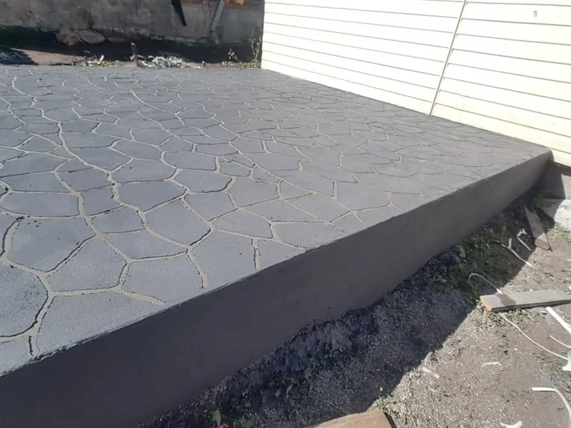 A stamped stone-pattern patio with a clean stepped concrete edge