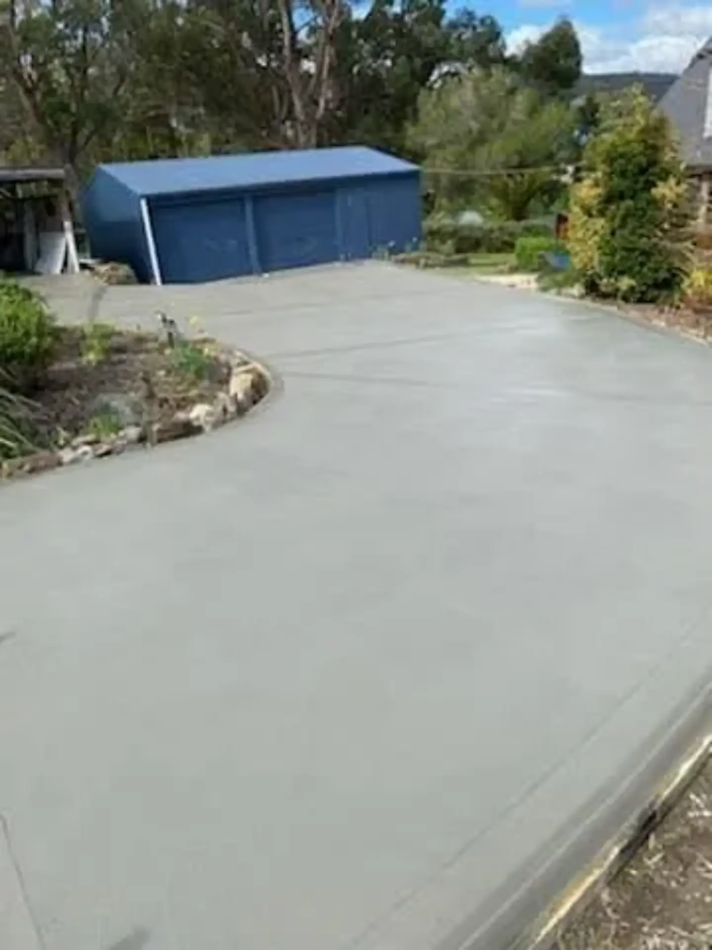 A broad finished concrete area laid in front of a rural shed
