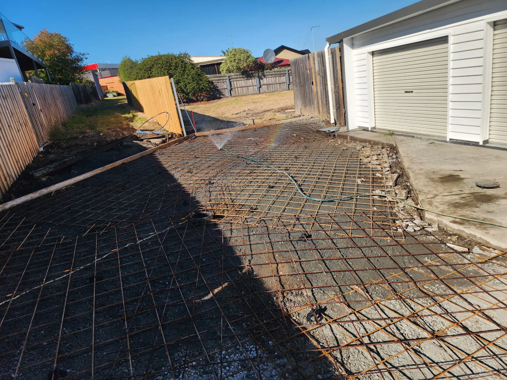 Reinforcing mesh laid out across a prepared driveway area in front of a garage