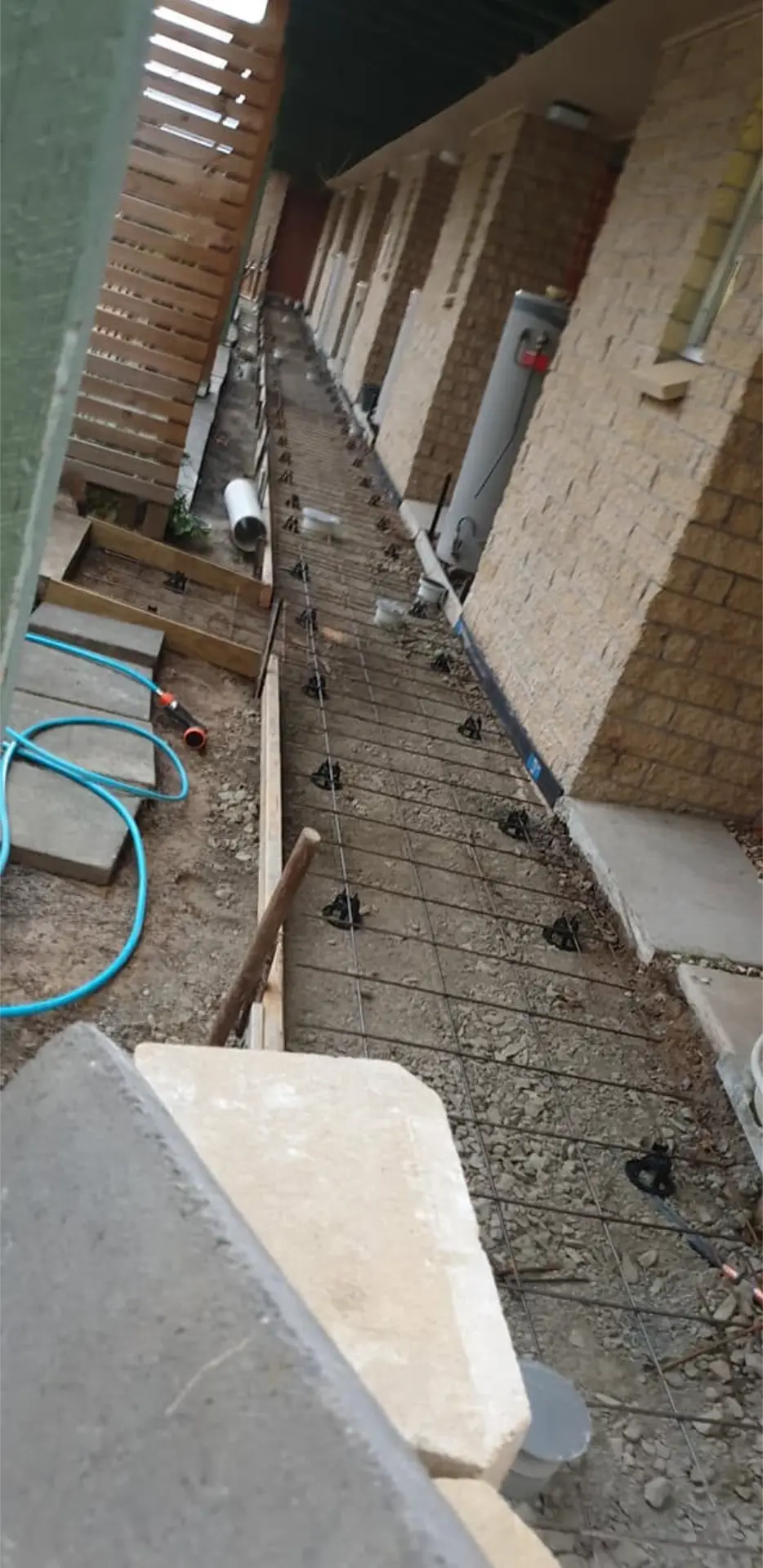 A finished concrete path running the length of a brick home