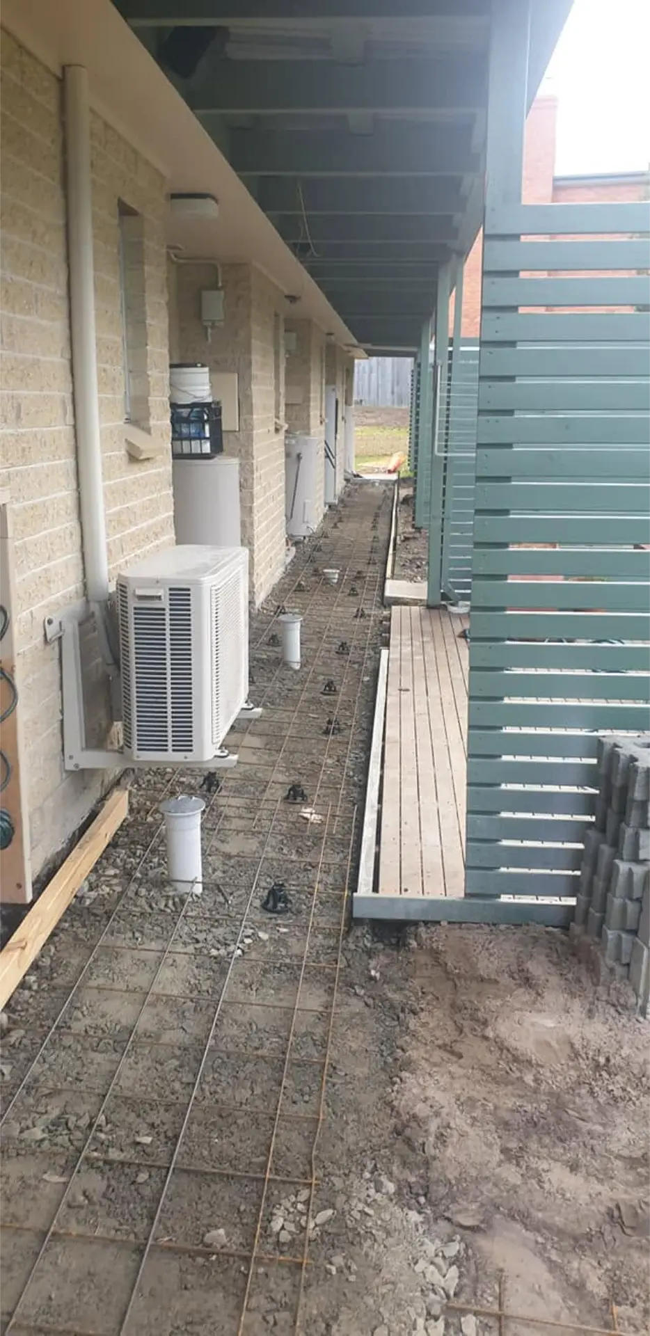 A narrow access path formed up beside a house before the final trowel