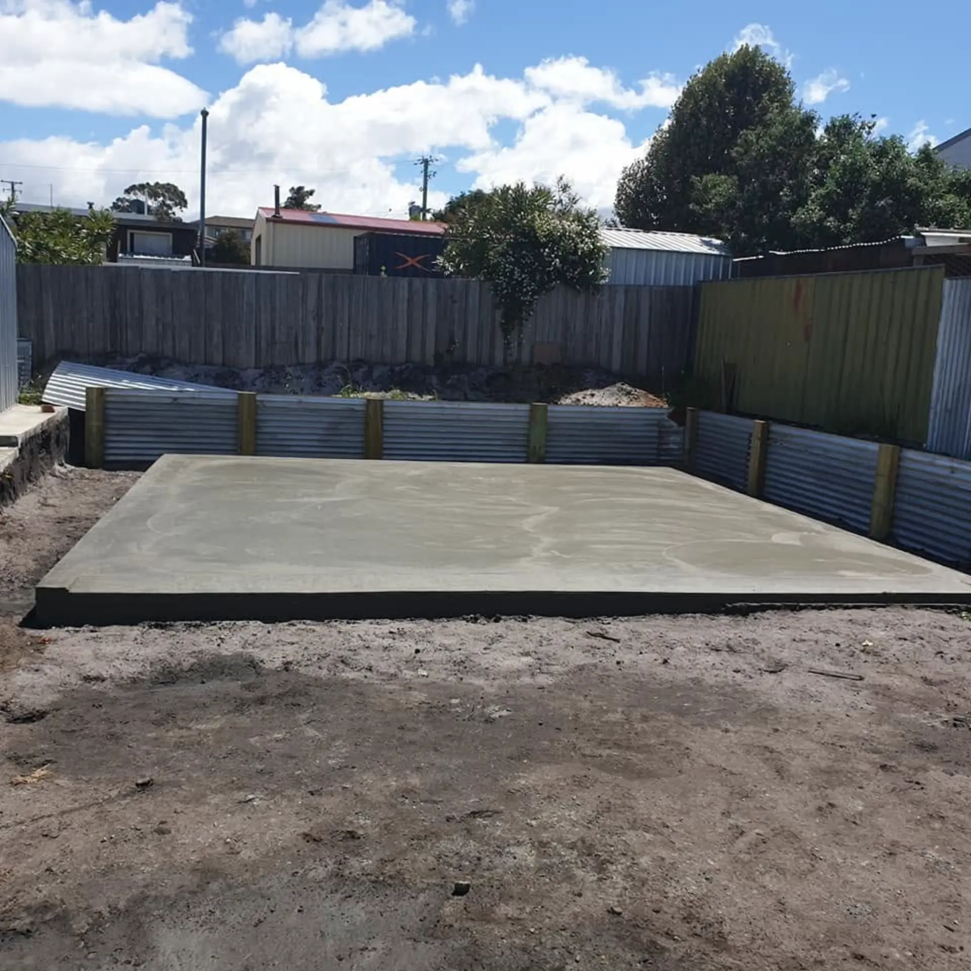 A finished slab pad boxed in timber with a fence and hills behind