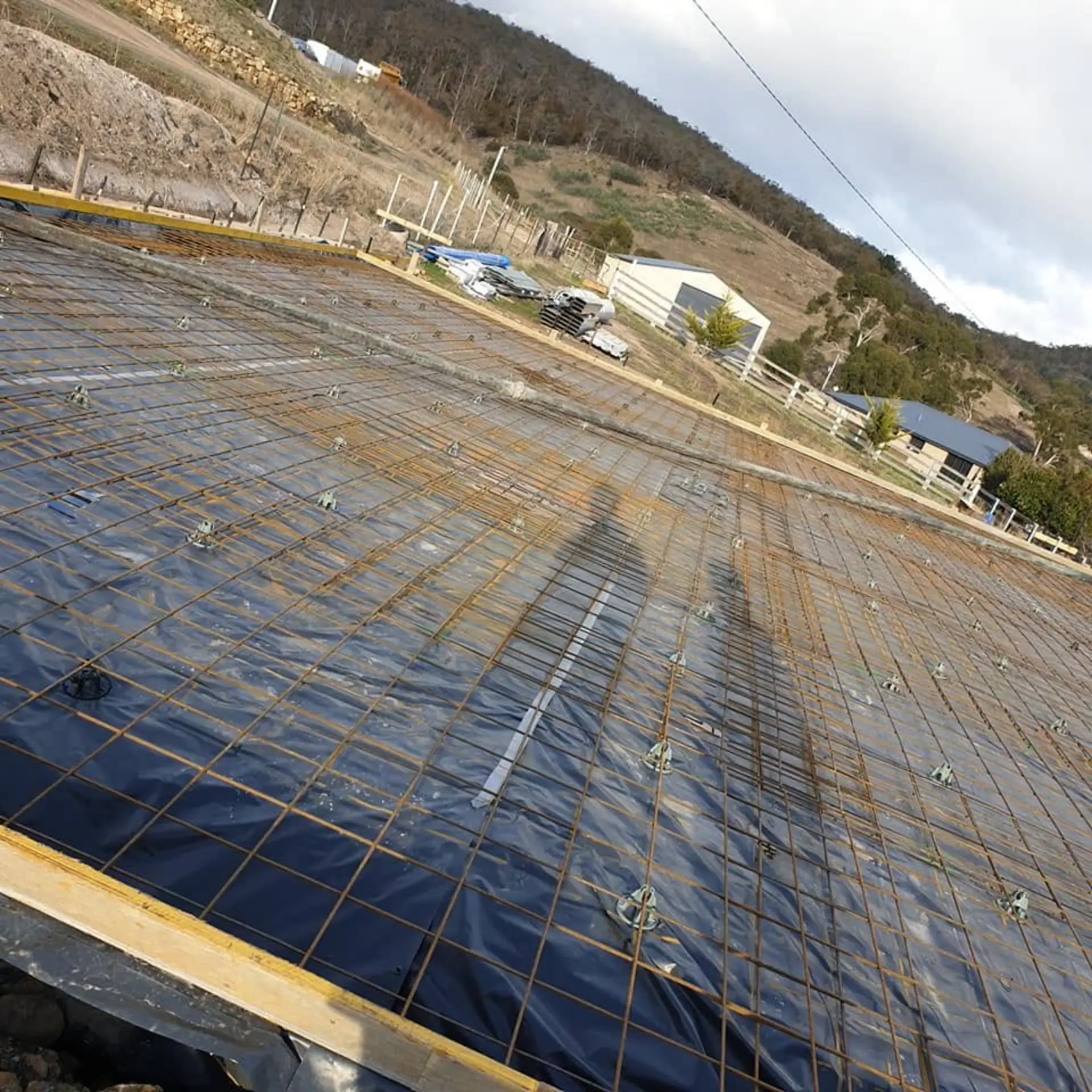 Reinforcing mesh laid over plastic membrane across a formed-up pad