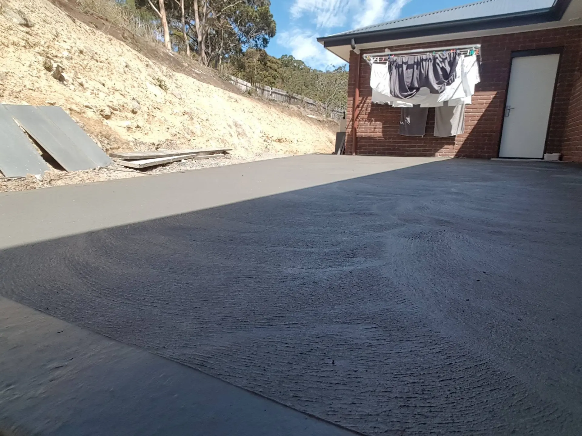 A dark-finished driveway running from the street up to a house garage