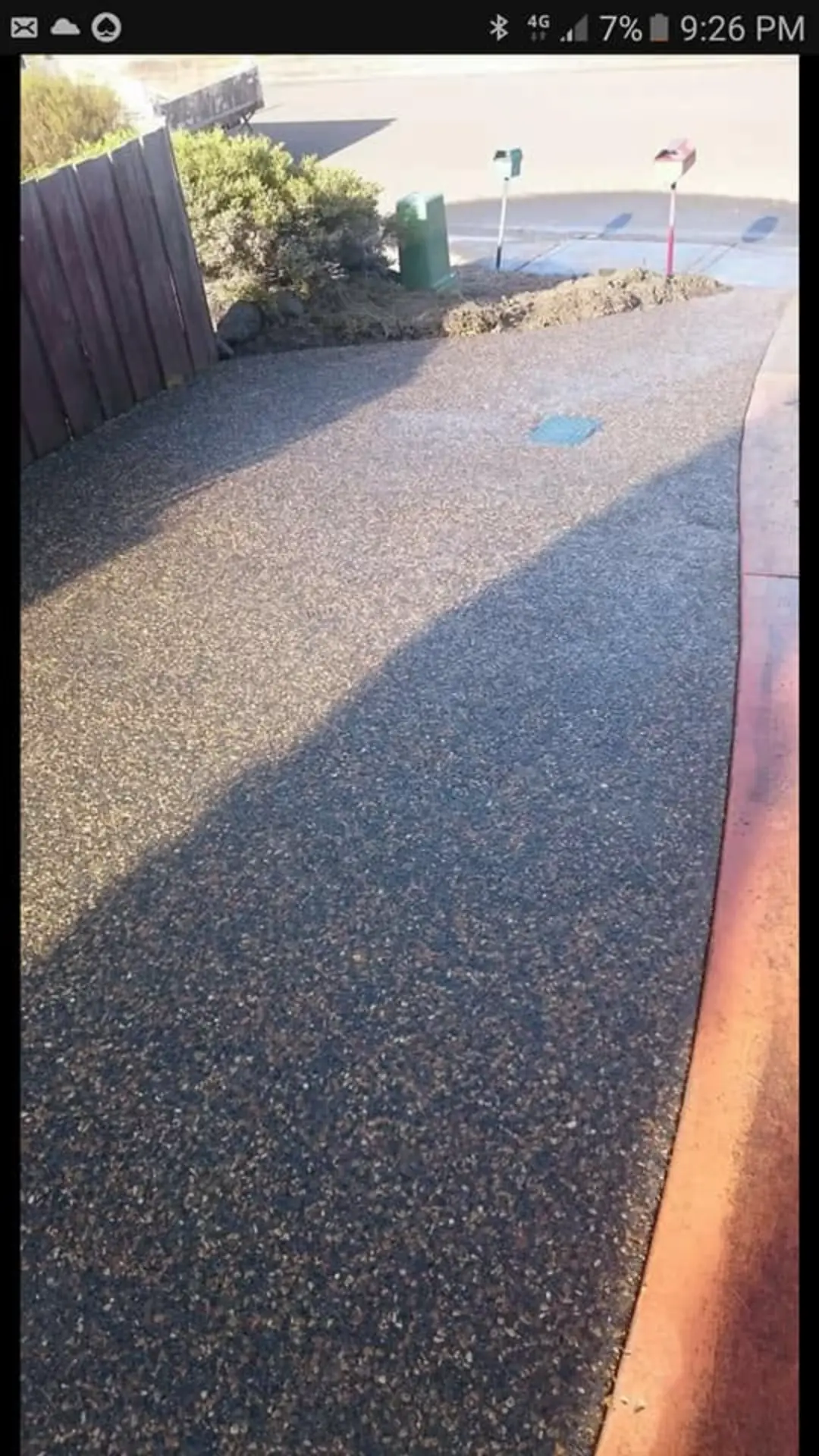 An exposed aggregate driveway finished with a red brick edge