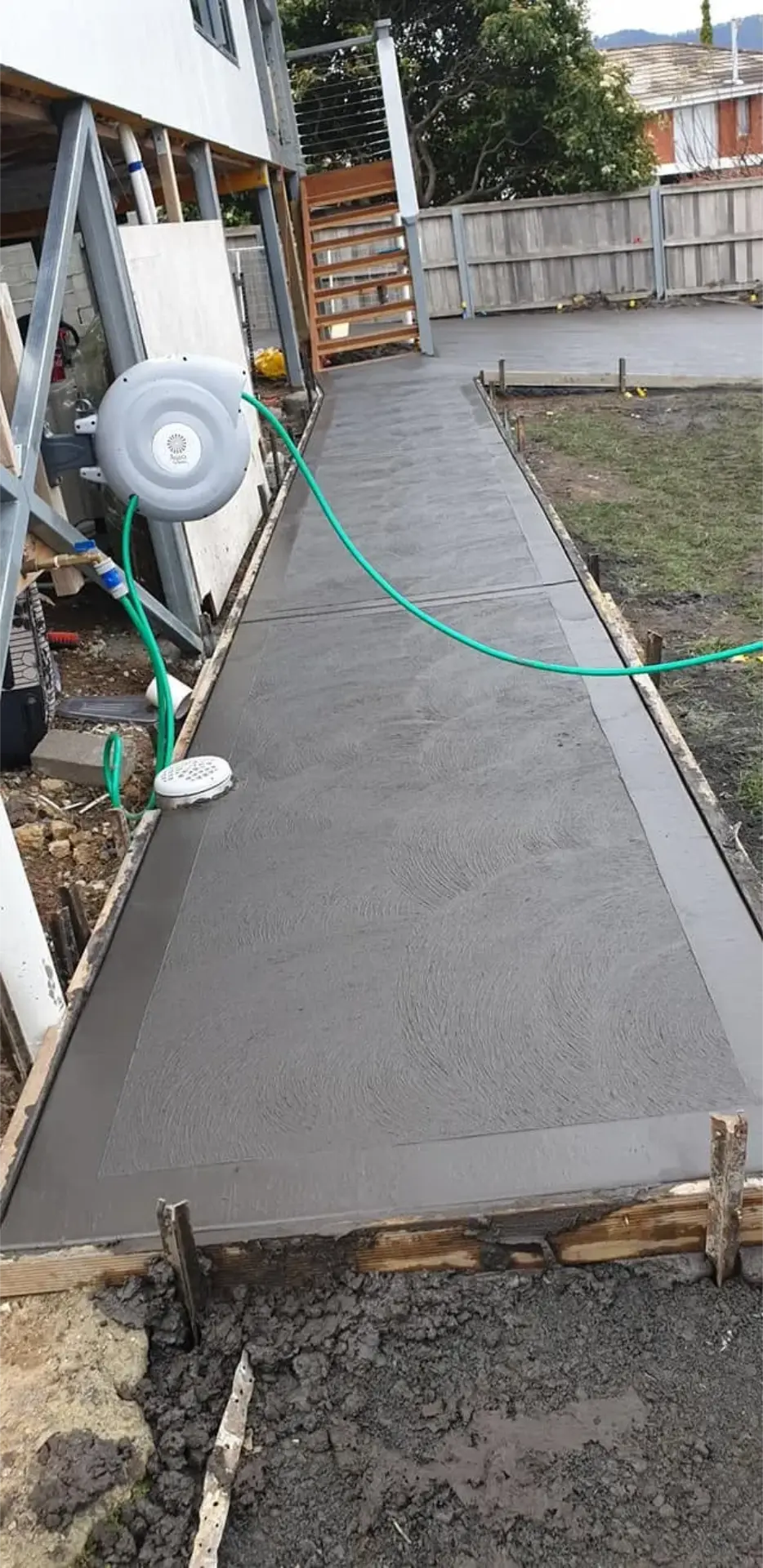 A concrete path laid down a tight side boundary to a rear yard