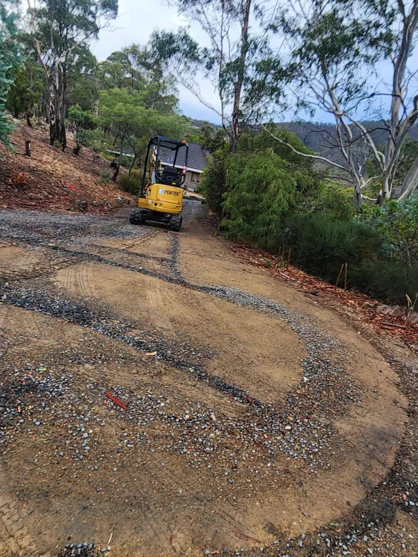 An excavator preparing a curved driveway run on a bush property