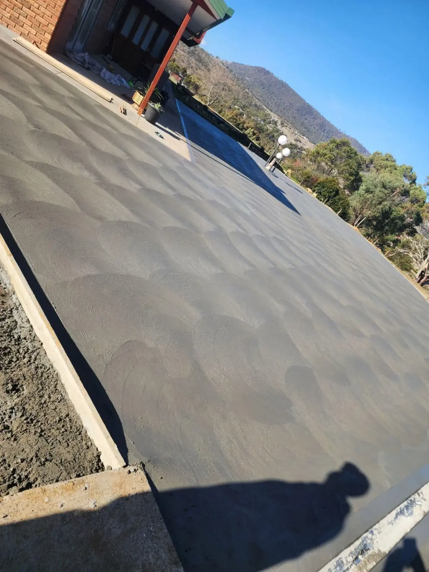 A large slab pad finished flat beside a brick house in clear sun