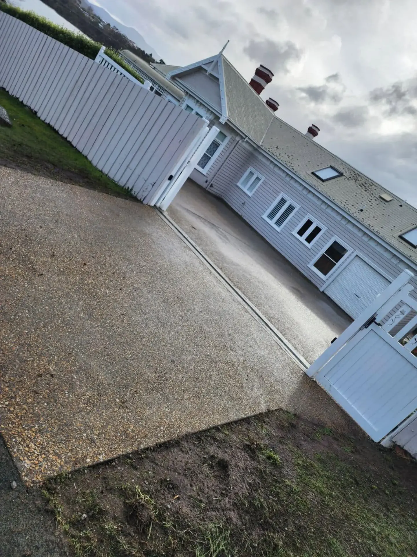 An exposed aggregate driveway running along the side of a white house