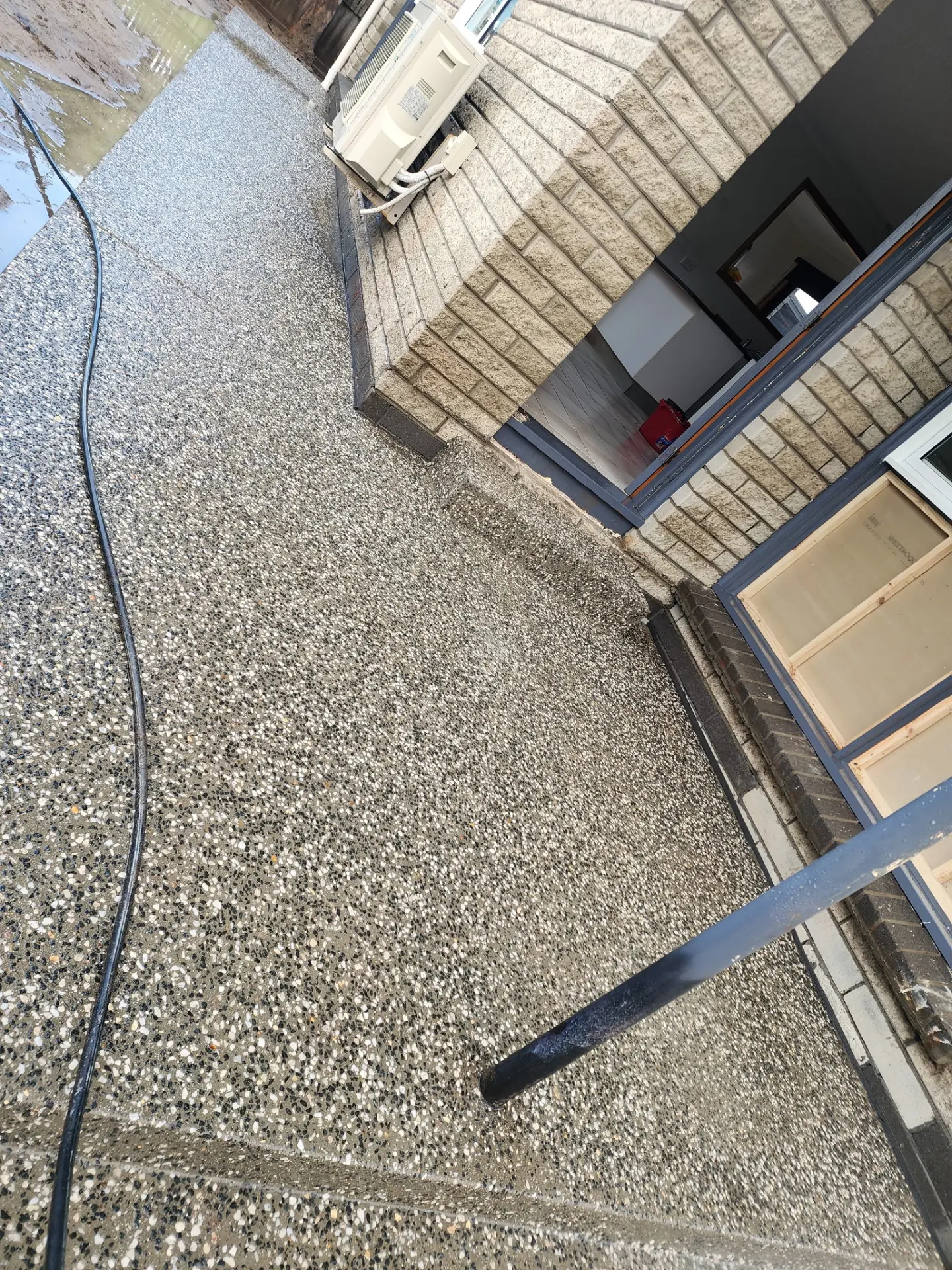 Washed stone aggregate exposed across a finished surface running past a brick entry