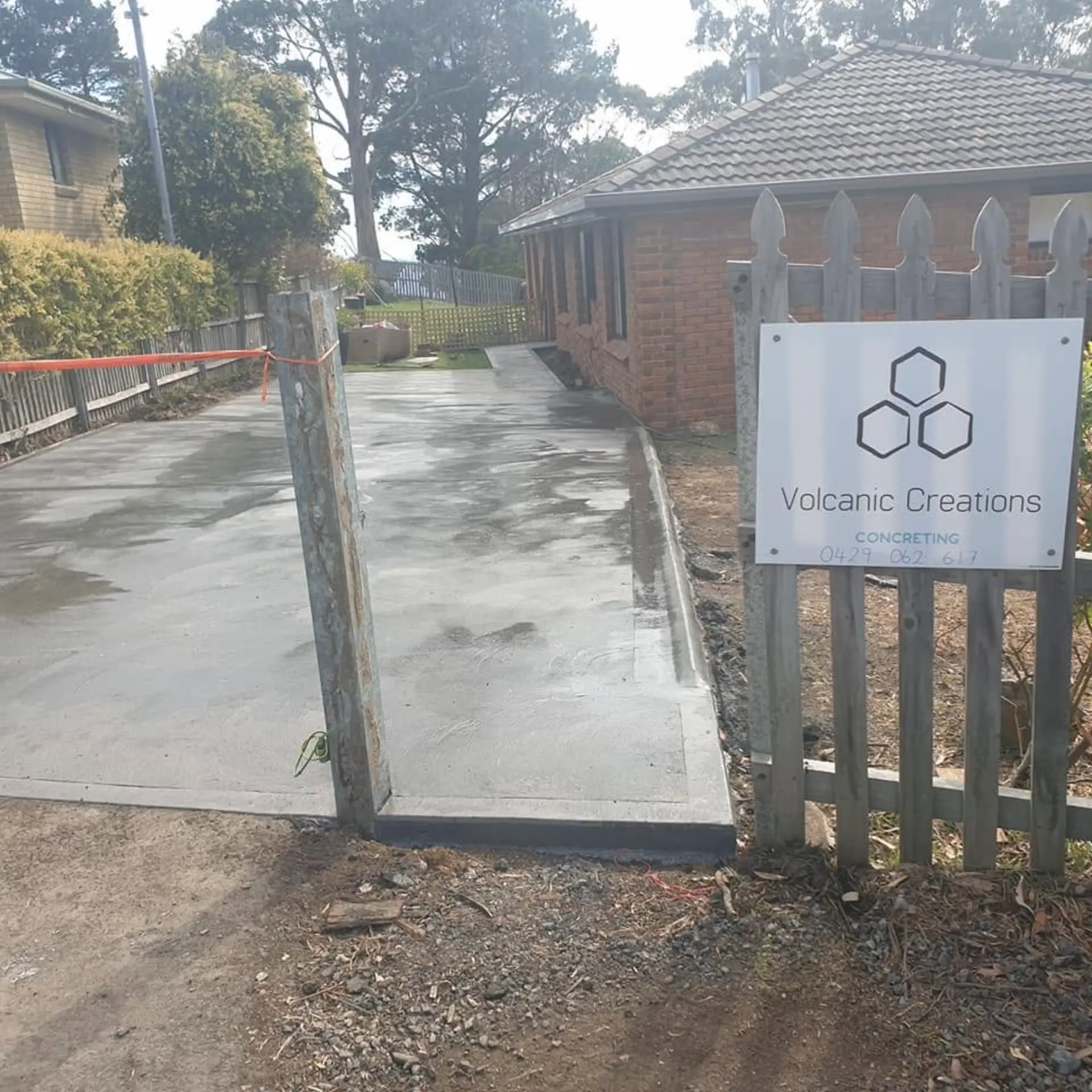 A concrete driveway and gate entry finished with the company sign on site