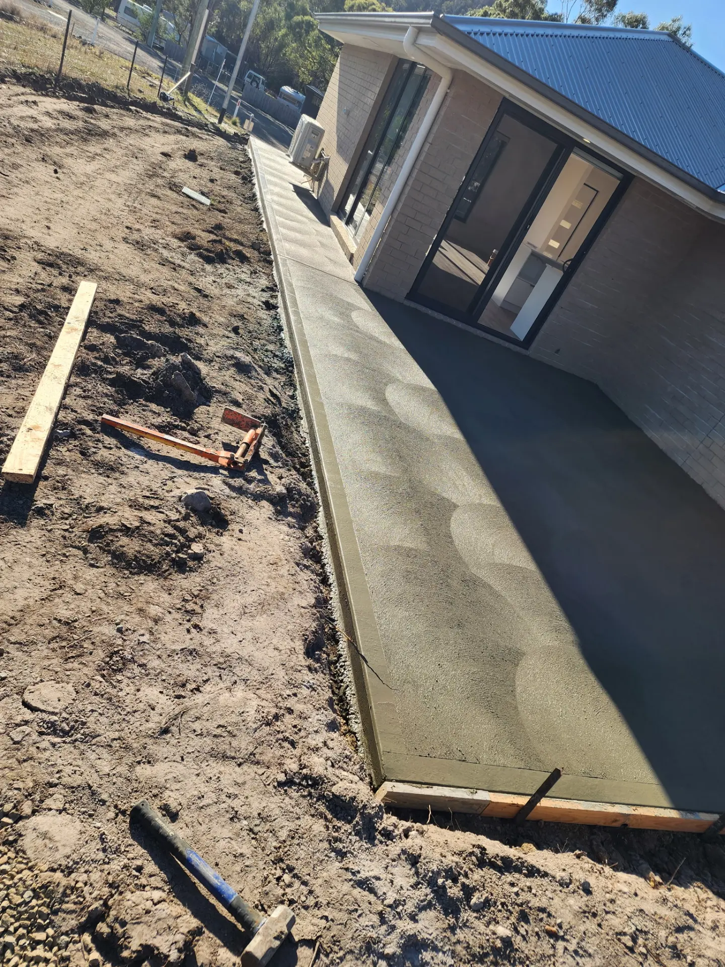 A formed concrete strip poured along the side of a new grey brick home